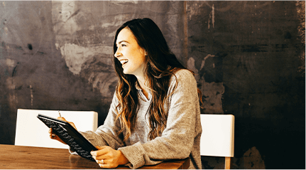 タブレットを持ちながら横を見て笑顔で話す女性